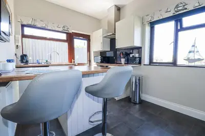 a kitchen with white cabinets and two white chairs at Jenny Wren in Par