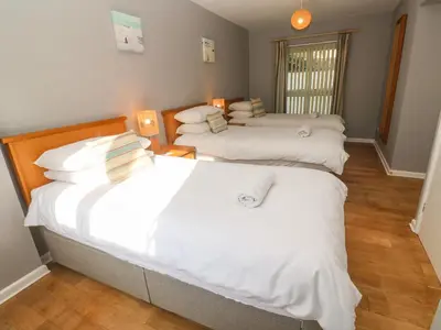a bedroom with three beds with white sheets at Beachcombers in Newquay
