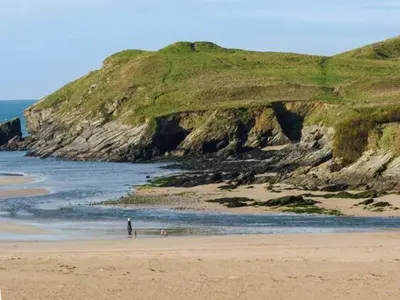 a person standing on a beach next to the ocean at Beachcombers in Newquay