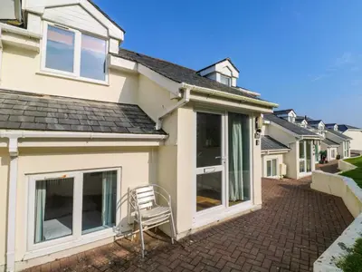 a house with sliding glass doors on a brick driveway at Beachcombers in Newquay