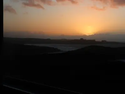 a sunset over the water with the sun setting in the background at Spindrift in Newquay
