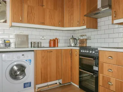 a kitchen with a washing machine and wooden cabinets at Spindrift in Newquay