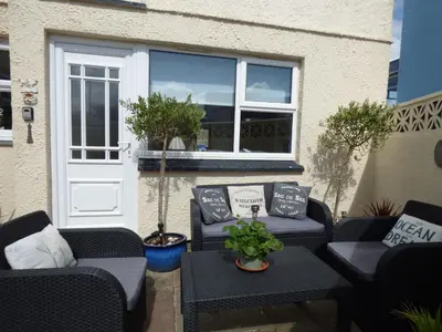 a patio with two chairs and a table and a door at Spindrift in Newquay