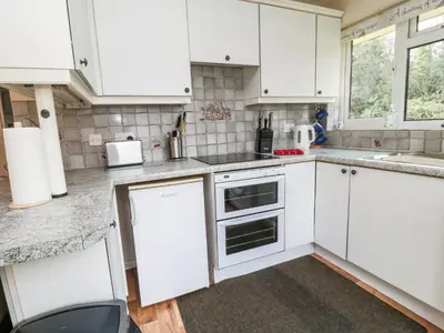 a kitchen with white cabinets and white appliances at Peacehaven in Liskeard