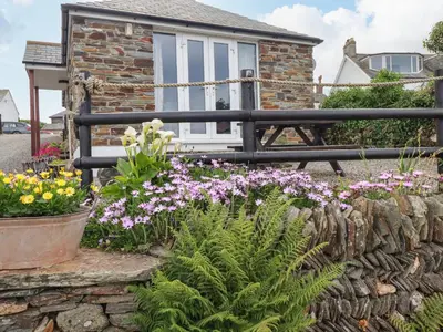 a garden with flowers in front of a house at Sunset Cottage in Tintagel