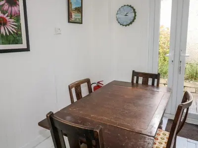 a dining room table with chairs and a clock on the wall at Driftwood in Wadebridge