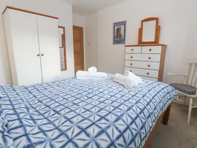 a bedroom with a blue and white bed and a dresser at Kernow Cottage in Helston