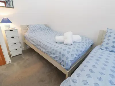 a bedroom with two twin beds and a night stand at Kernow Cottage in Helston