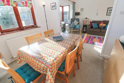 a dining room with a table with chairs and a couch at Kernow Cottage in Helston