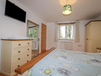 a bedroom with a bed and a dresser and a television at Vine Cottage in Saint Ewe