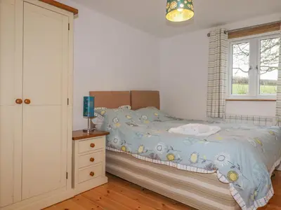 a bedroom with a bed and a dresser and a window at Vine Cottage in Saint Ewe