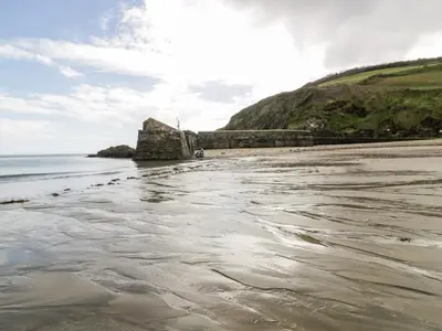 a beach with a rock in the water at Honeysuckle in Gorran Haven