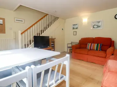 a living room with a red couch and a table at Honeysuckle in Gorran Haven