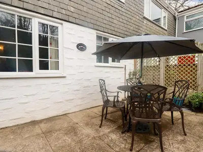 a table and chairs with an umbrella on a patio at Honeysuckle in Gorran Haven