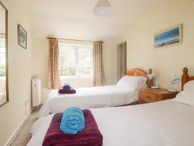 a bedroom with three beds and a window at Honeysuckle in Gorran Haven