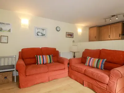 two orange chairs and a couch in a living room at Honeysuckle in Gorran Haven