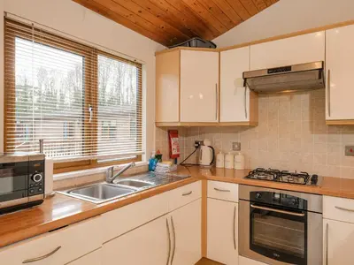 a kitchen with white cabinets and a sink and a window at High Tide in Wadebridge