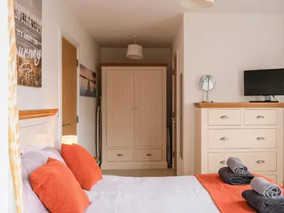 a bedroom with a bed with orange pillows and a tv at Stone's Throw in Charlestown