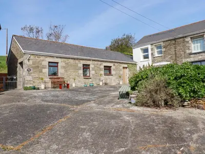 a stone house with a parking lot in front of it at Stable Cottage in Newquay