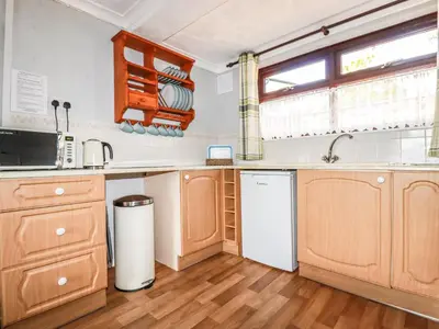 a kitchen with wooden cabinets and a white refrigerator at Stable Cottage in Newquay