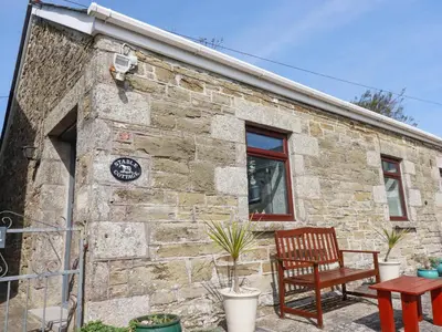a stone cottage with a bench and a window at Stable Cottage in Newquay