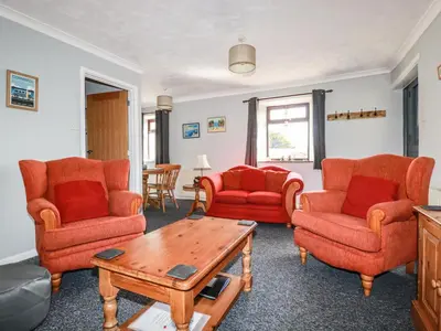 a living room with orange chairs and a table at Stable Cottage in Newquay