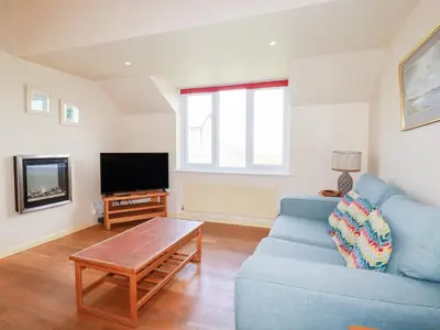 a living room with a blue couch and a tv at The Beach House in Newquay