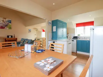 a kitchen and living room with a wooden table and a dining room at The Beach House in Newquay