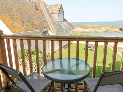 a table and chairs on a balcony with a view of the ocean at The Beach House in Newquay