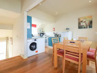a kitchen and dining room with a table and a washing machine at The Beach House in Newquay