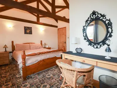 a bedroom with a bed and a mirror on the wall at Kingfisher Barn in Liskeard