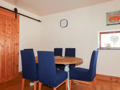 a dining room with a wooden table and blue chairs at Kingfisher Barn in Liskeard