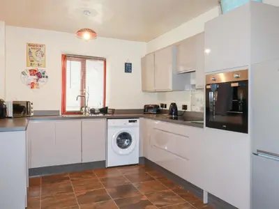a kitchen with a washer and dryer in it at Kingfisher Barn in Liskeard