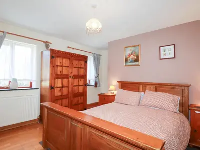 a bedroom with a wooden bed and a window at Kingfisher Barn in Liskeard