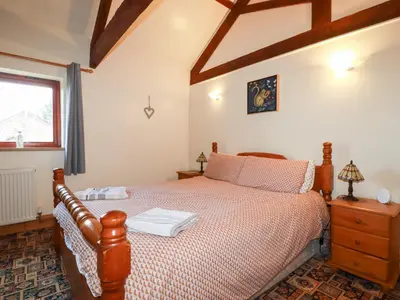 a bedroom with a bed and a window at Kingfisher Barn in Liskeard