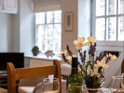 a table with a bottle of wine and flowers on it at Cobble Cottage in Boscastle