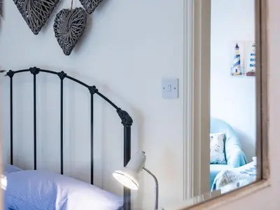 a bedroom with a mirror and a bed and a lamp at Cobble Cottage in Boscastle