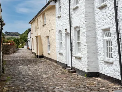 a cobblestone street in a village with white houses at Cobble Cottage in Boscastle