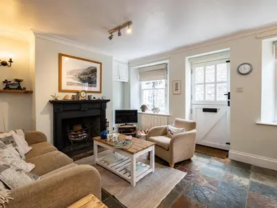a living room with a couch and a fireplace at Cobble Cottage in Boscastle