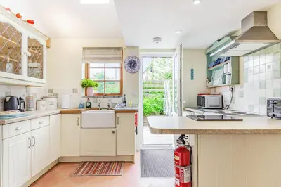 a large kitchen with white cabinets and a window at Victoria Cottage in Newquay