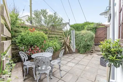 a patio with a table and chairs and a fence at Victoria Cottage in Newquay