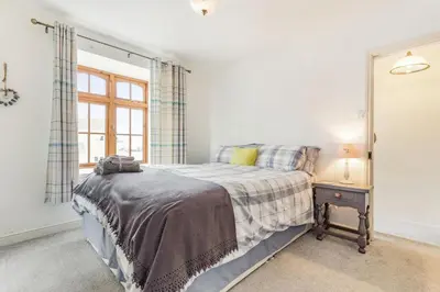 a bedroom with a bed with a nightstand and a window at Victoria Cottage in Newquay