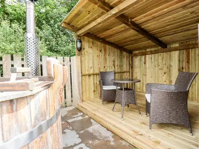 a wooden pergola with chairs and a table on a patio at Bramble in Wadebridge
