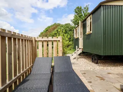 a green trailer and benches next to a fence at Bramble in Wadebridge