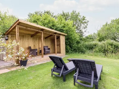 a wooden shed with two chairs and a table in the grass at Willow in Wadebridge