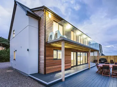 a wooden house with a table on a deck at Chy Lowen in St Ives