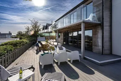 a deck with white chairs and tables on a house at Chy Lowen in St Ives