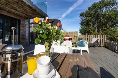 a wooden table with a vase of flowers on a deck at Chy Lowen in St Ives