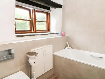 a bathroom with a tub and a toilet and a window at Meadow Lea in Liskeard