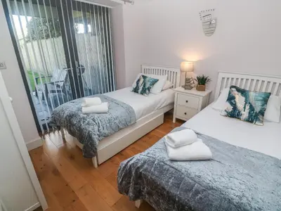 a bedroom with two beds and a balcony at Seafield in Carbis Bay